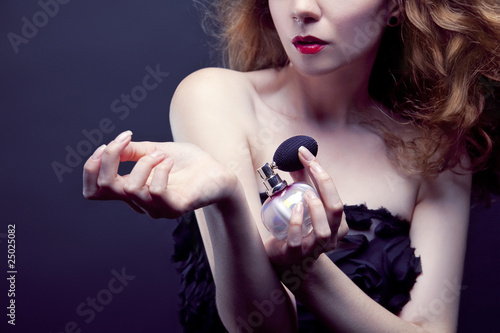 beautiful woman applying perfume on her body photo