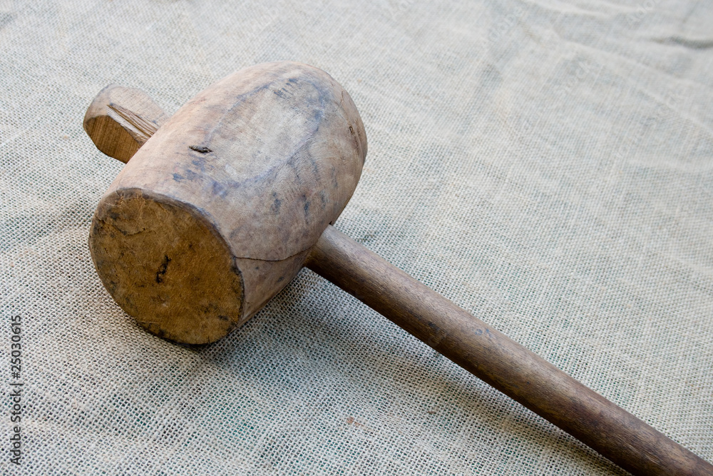 Old wooden mallet hammer on burlap background