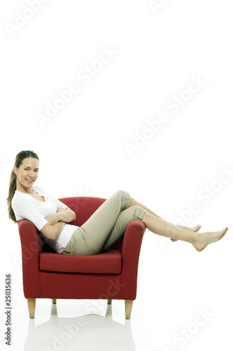 Young woman sitting on a chair on white background studio © Ambrophoto