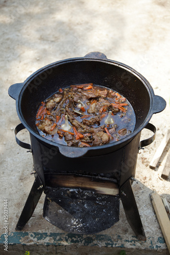 cooking pilaf in a cast iron cauldron over a fire