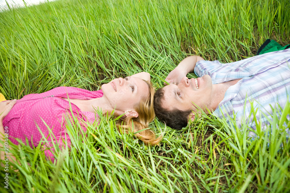 Young love couple lay on the green grass outdoors Young love couple lay on the green grass outdoors