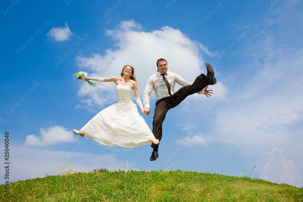 Groom and bride jumping against backdrop a sky and trees Groom and bride jumping against backdrop a sky and trees