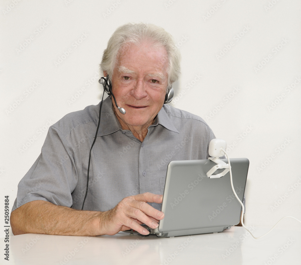 Älterer Herr mit Netbook, Webcam und Headset Älterer Herr mit Netbook, Webcam und Headset