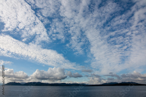 panorama with a lot of sky and clouds  the sea blue and mountains in the background in a summer day in Norway