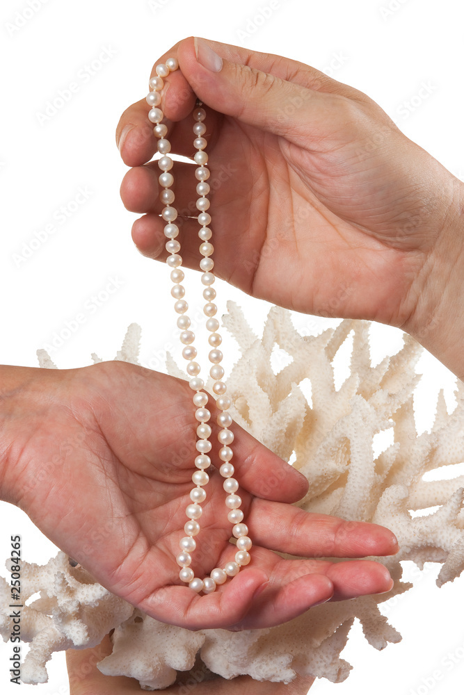 a pearl necklace in her hands against the backdrop of coral a pearl necklace in her hands against the backdrop of coral