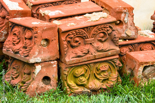 Antique molded bricks stacked on grass.