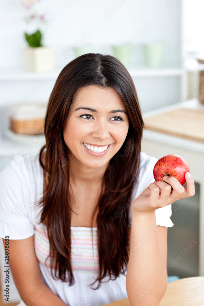 Radiant asian woman holding an apple in the kitchen Radiant asian woman holding an apple in the kitchen