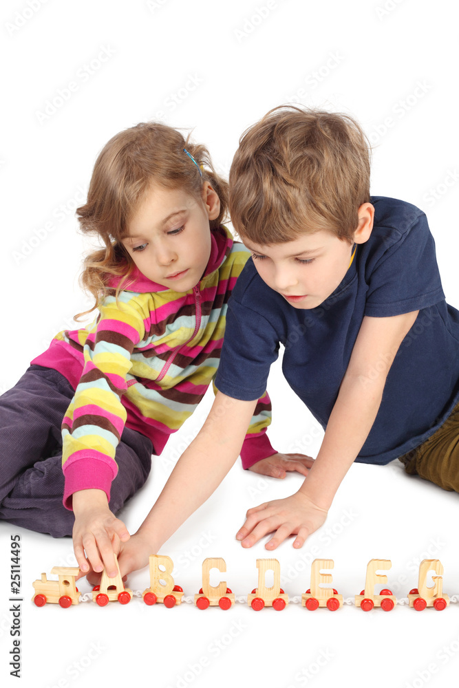 Naklejka premium boy and girl playing with wooden railway sitting on floor
