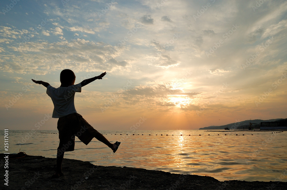 The silhouette of child against the sunset at sea