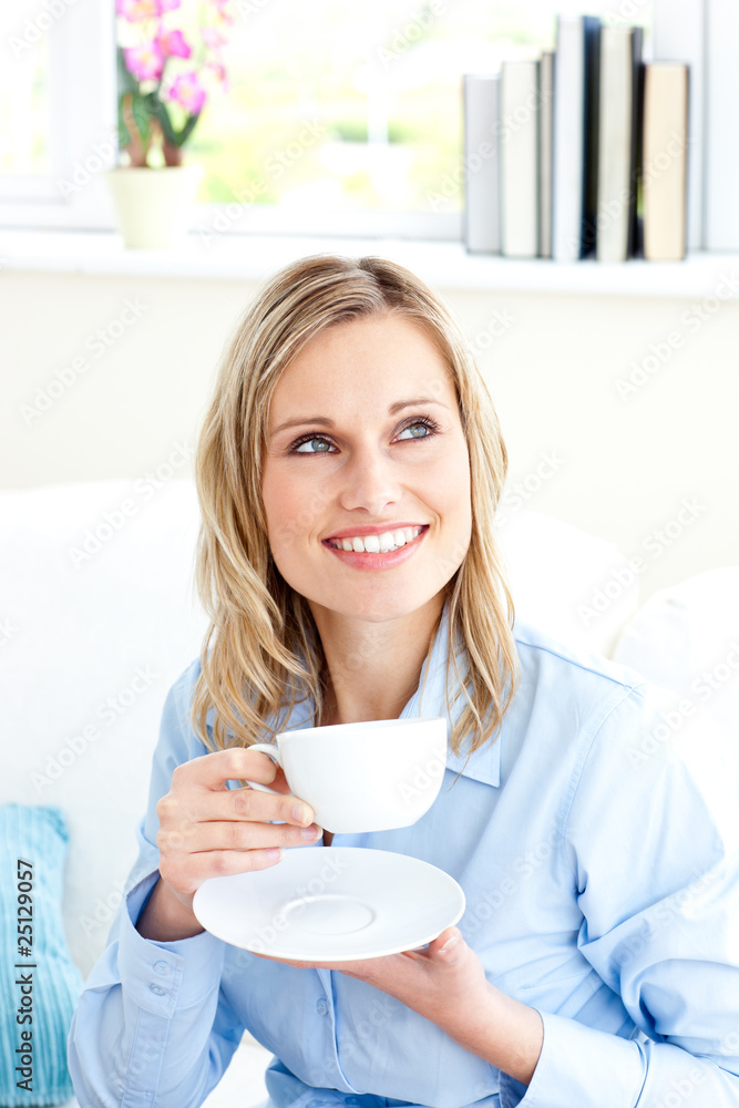 Captivating businesswoman holding a cup sitting on a sofa Captivating businesswoman holding a cup sitting on a sofa