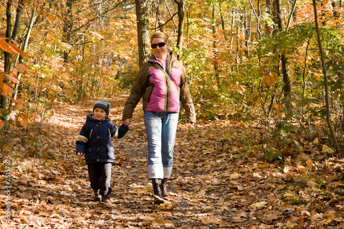 Mother and son taking a walk in autumn forest