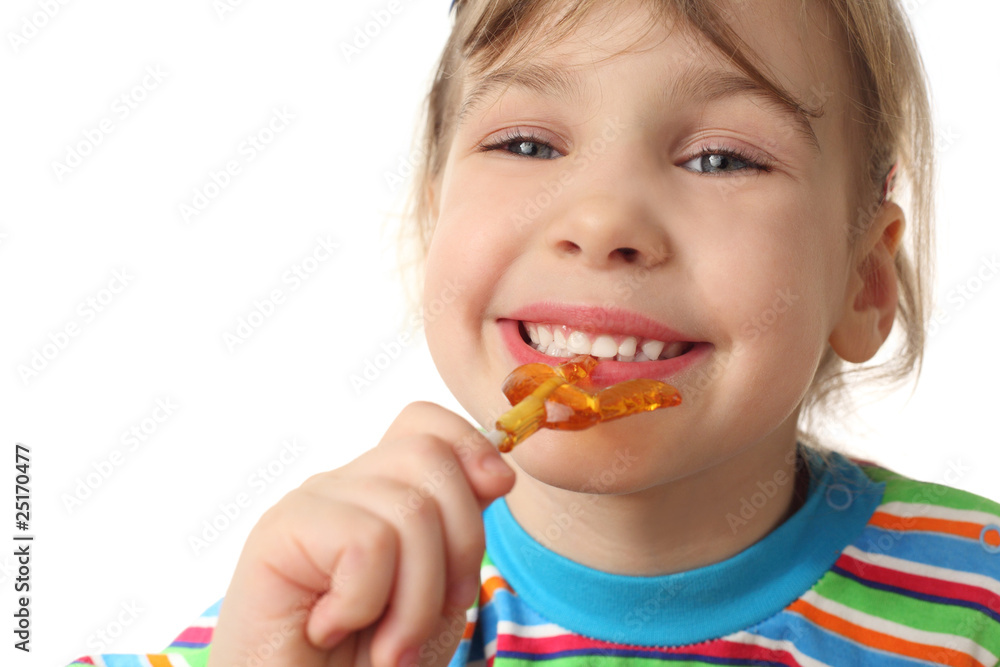 little girl eating orange lollipop, smiling and looking little girl eating orange lollipop, smiling and looking