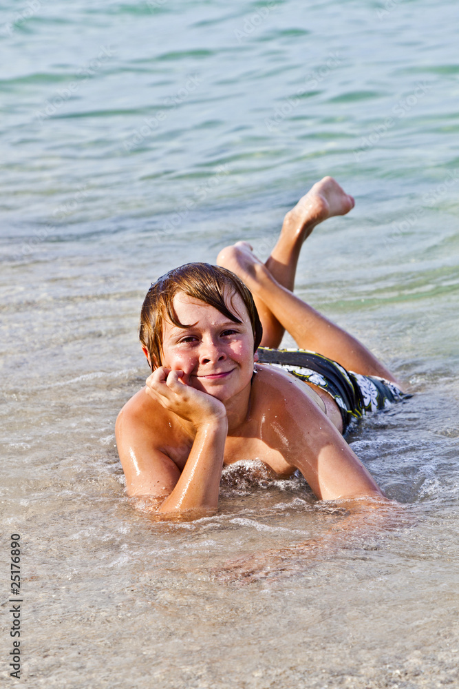 boy enjoys lying at the beach in the surf boy enjoys lying at the beach in the surf