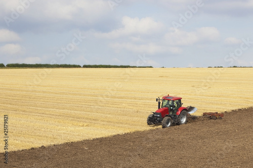 red tractor plowing a field