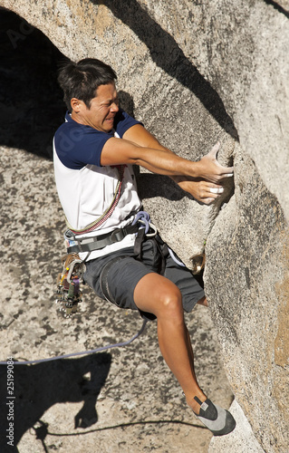 Rock climber clinging to steep cliff.
