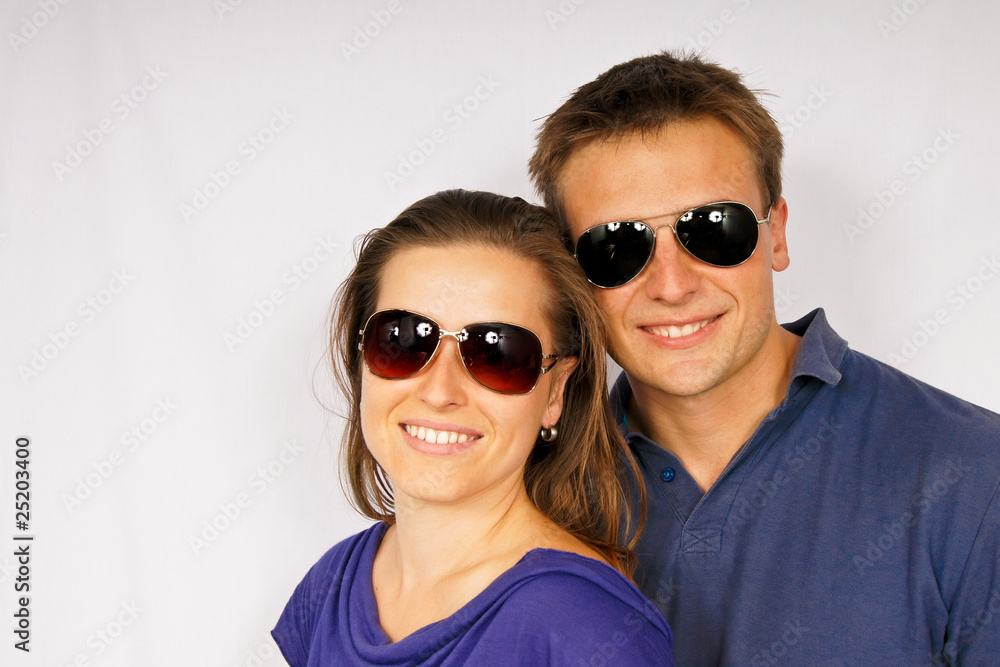 Portrait of young couple in sunglasses on light background Portrait of young couple in sunglasses on light background