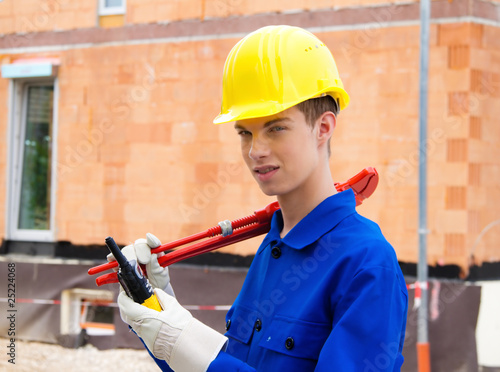 Lehrling / Azubi. Bauarbeiter auf Baustelle mit Helm. photo