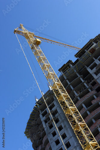 Building tower crane in action against a blue sky