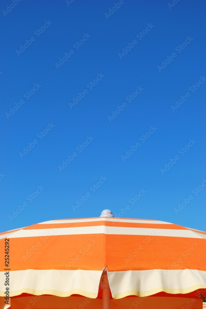 Orange striped beach umbrella on blue sky, Rimini, Italy