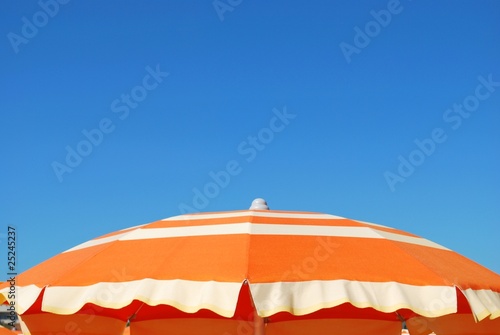 Obraz na płótnie Orange striped beach umbrella on blue sky, Rimini, Italy w salonie