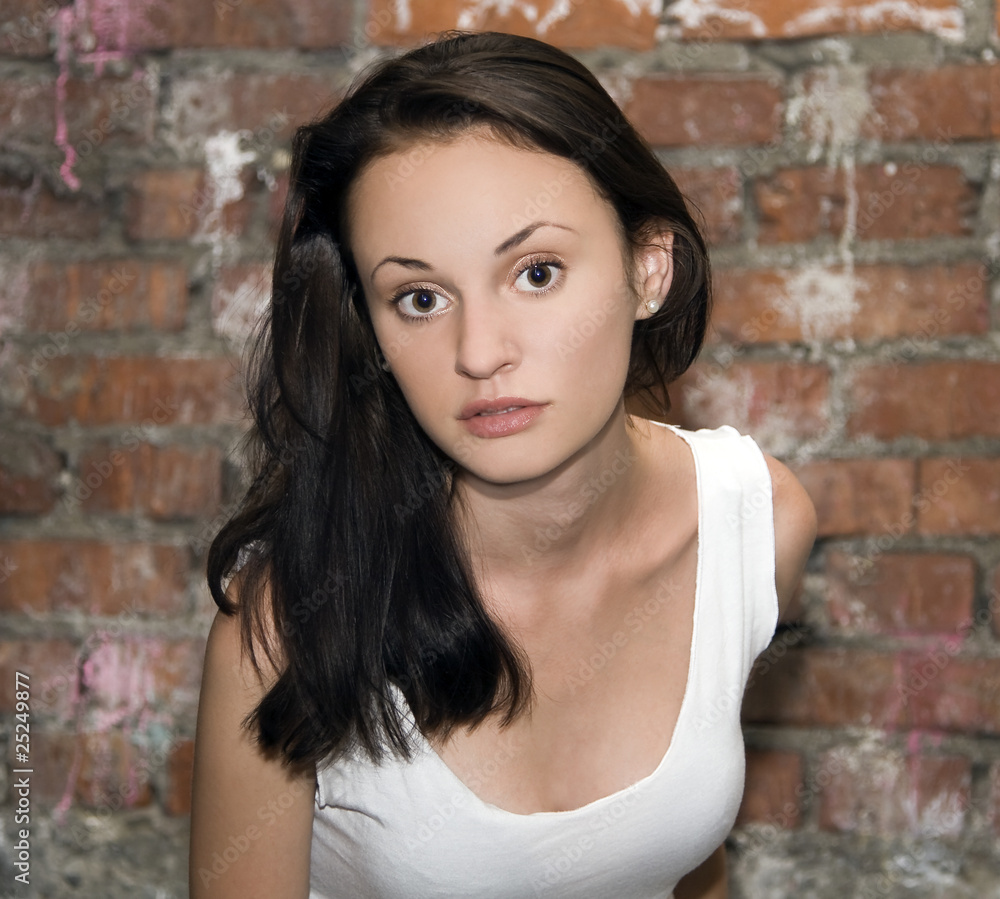fashion portrait of young woman with a brick wall in the backgro fashion portrait of young woman with a brick wall in the backgro