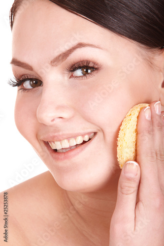 Young woman washing her face by sponge.