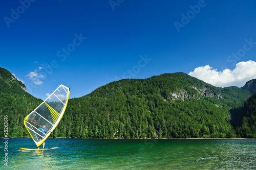 Windsurfer on mountain lake. Copyspace on blue sky. photo