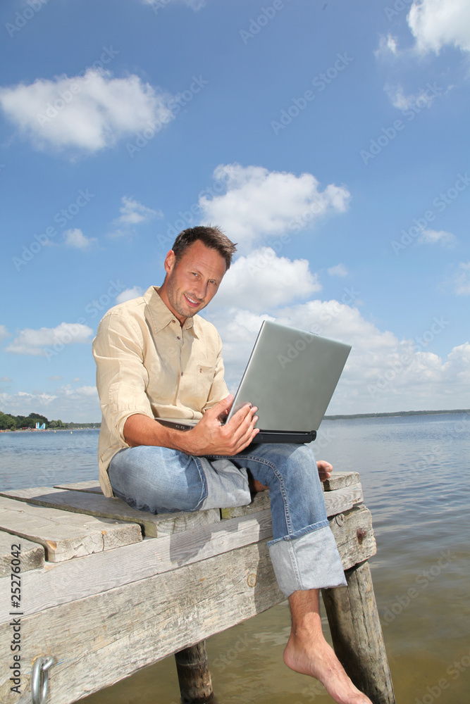 Man using laptop computer on a pontoon