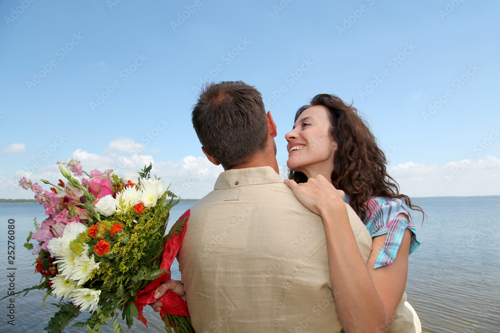 Man surprising woman with bunch of flowers