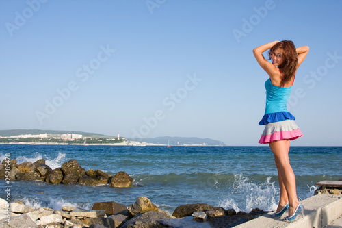 A slender young woman in a bright dress on the background of the