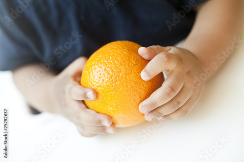 Babyhände greifen eine Orange