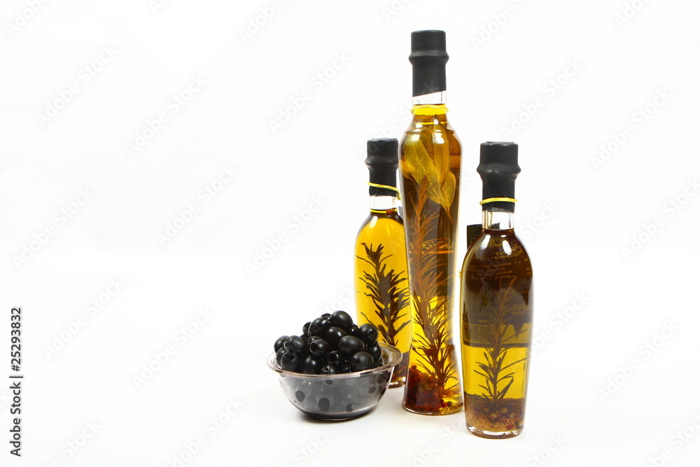 A bottle of olive oil with herbs and black olives A bottle of olive oil with herbs and black olives