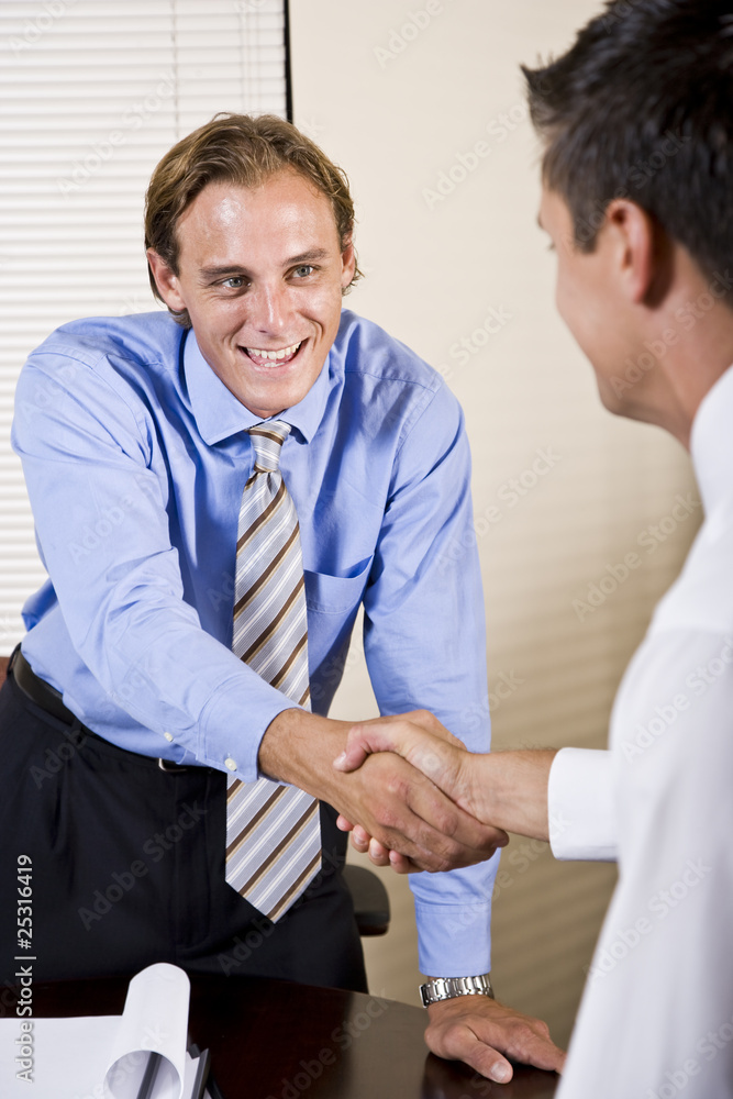 Two businessmen in office shaking hands
