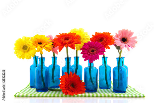 Row blue glass vases with colorful Gerber