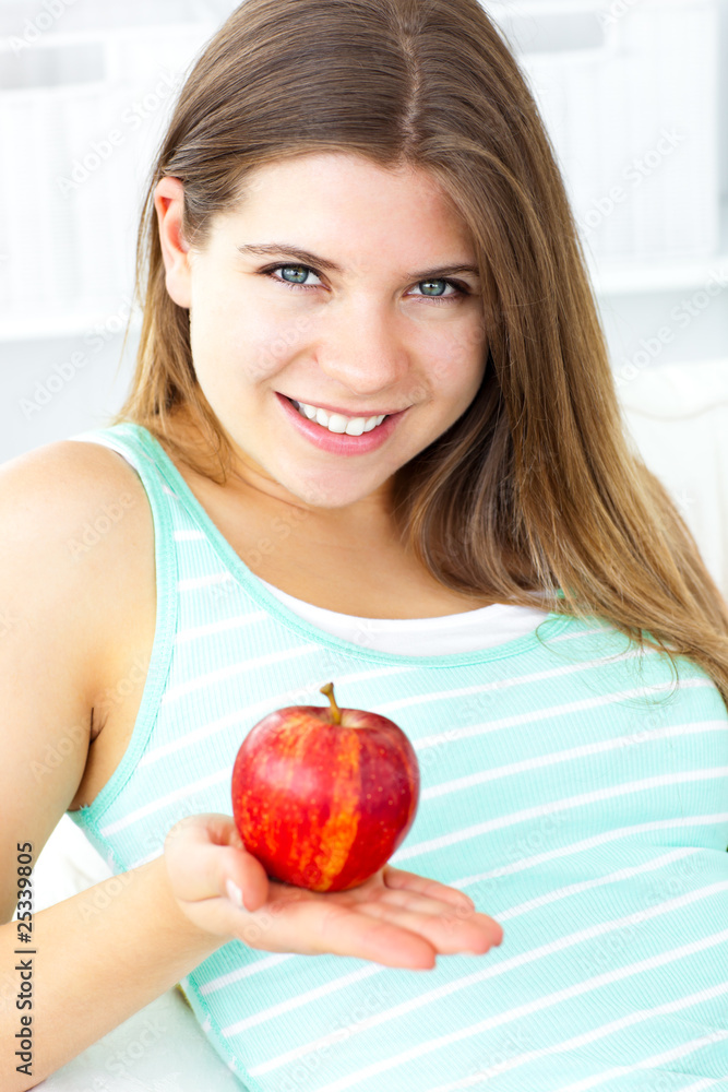 Pretty caucasian woman holding an apple sitting on a sofa Pretty caucasian woman holding an apple sitting on a sofa