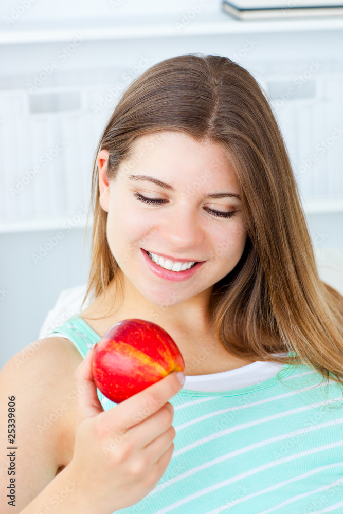 Charming caucasian woman holding an apple sitting on a sofa Charming caucasian woman holding an apple sitting on a sofa