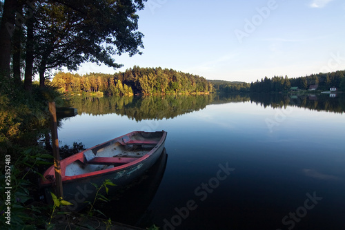 Evening summer countryside with pond, boat, forest and blue sky