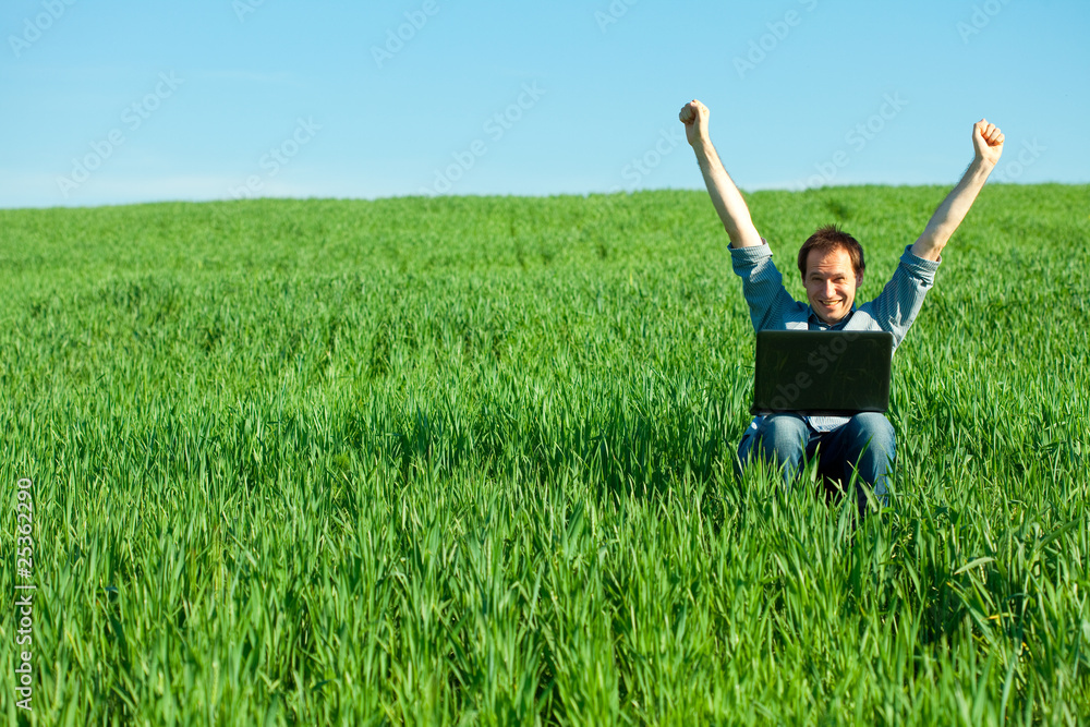 young man using laptop in the field young man using laptop in the field