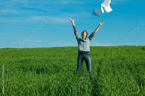 young man throwing a paper in the green field © Evgeniya Uvarova