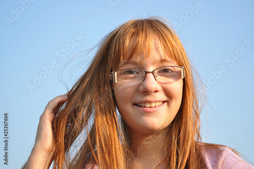 Beautiful, red-haired, young girl happy, blue sky background