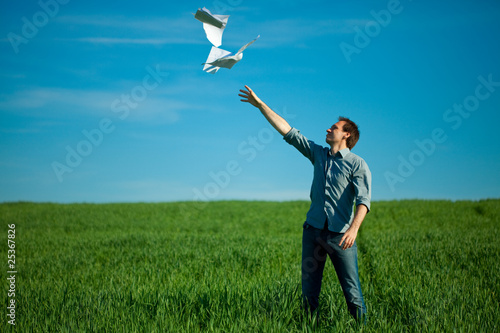 young man throwing a paper in the green field