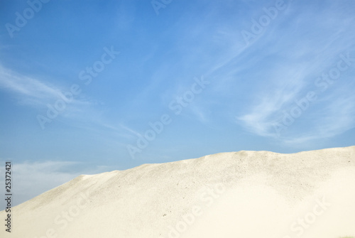 Sandy horizon against blue sky with clouds.