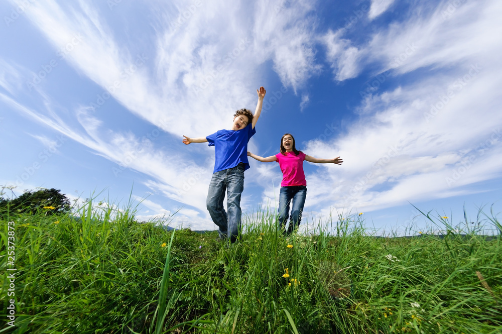 Girl and boy jumping, running against blue sky Girl and boy jumping, running against blue sky