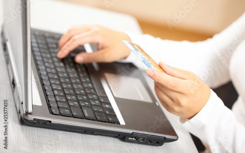 Hands holding credit card and laptop. Shallow DOF