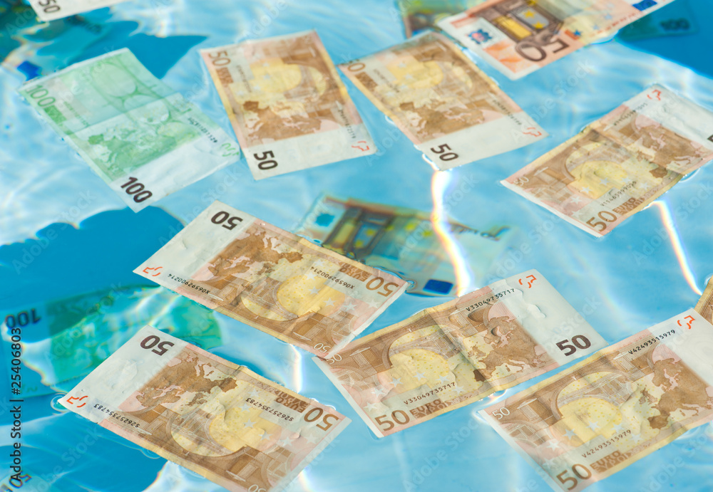 Money in water, floating and sinking. Close-up shot of Euros