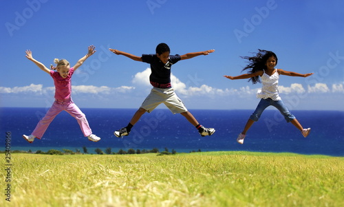 Trio d enfants sautant dans l herbe.