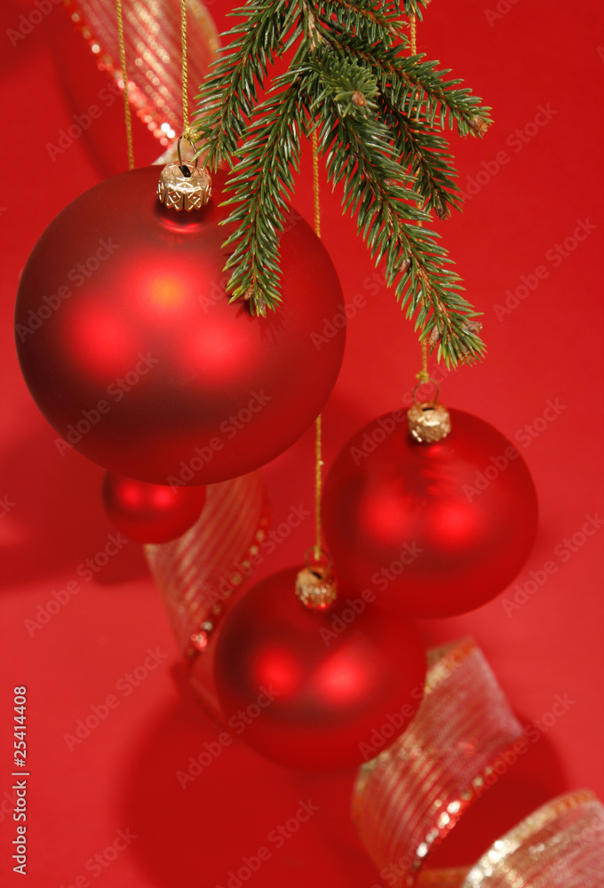 Hanging red glass balls with the ribbon on the red background