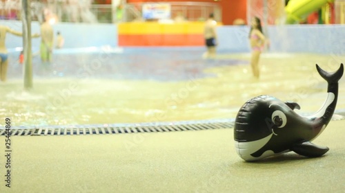 Inflatable whale is near pool, where children bathe photo