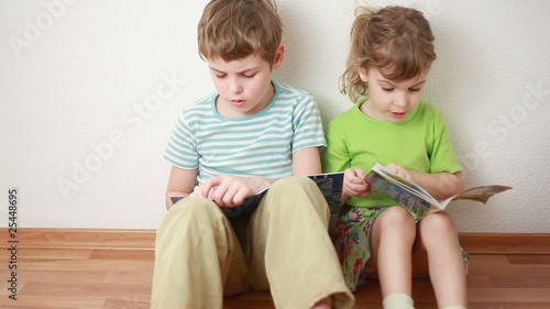 boy and girl sit leaning against wall and read books photo