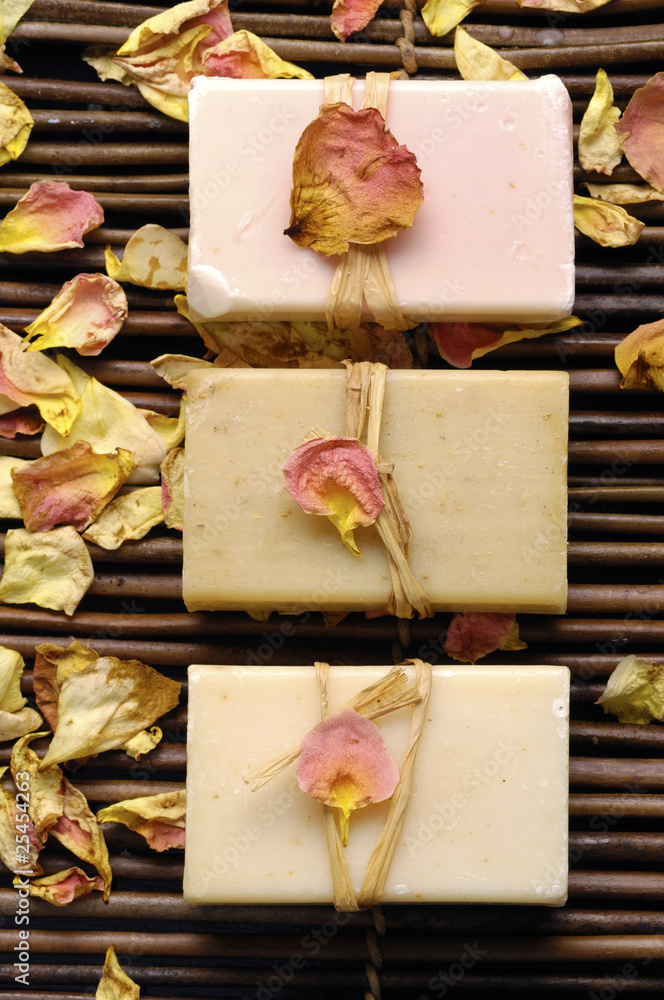 Row of soap and rose withered petals on bamboo mat Row of soap and rose withered petals on bamboo mat